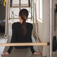 ピラティスマシンに向き合い、背筋を伸ばして呼吸を整える女性の後ろ姿